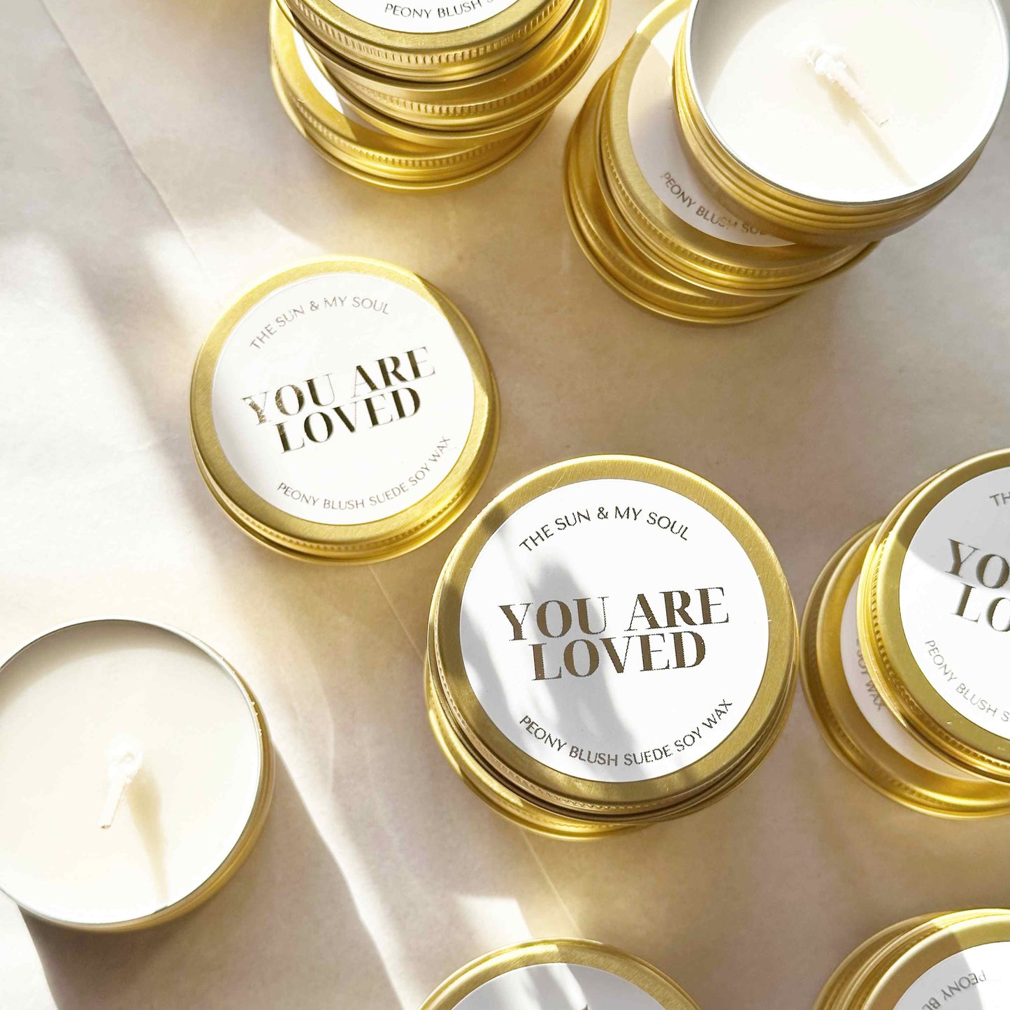 Candle jars with 'You Are Loved' labels on a light background
