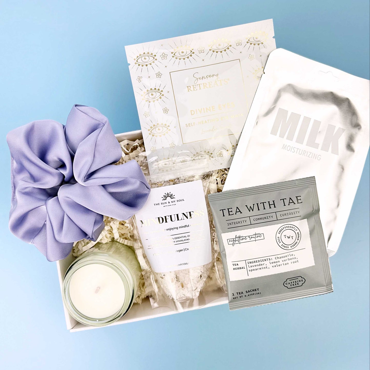 Gift set with tea, candle, and scrunchie on a blue background