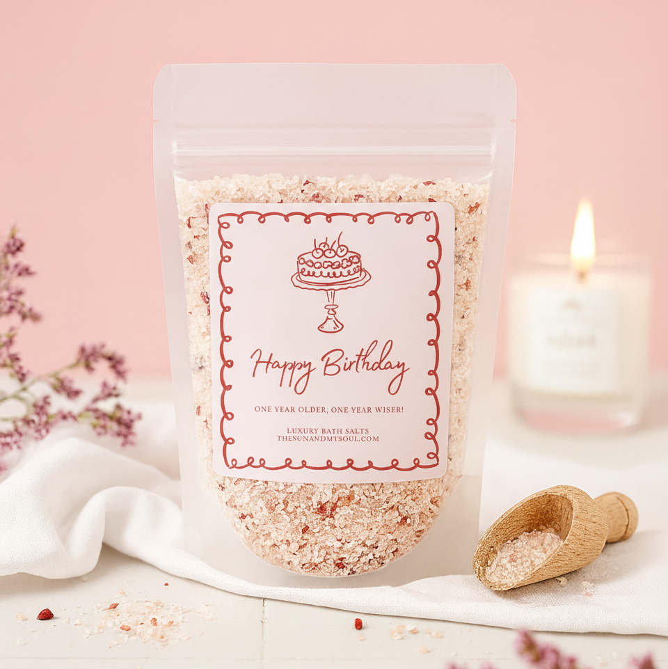 Packaged birthday-themed bath salts with a candle and flowers on a pink background