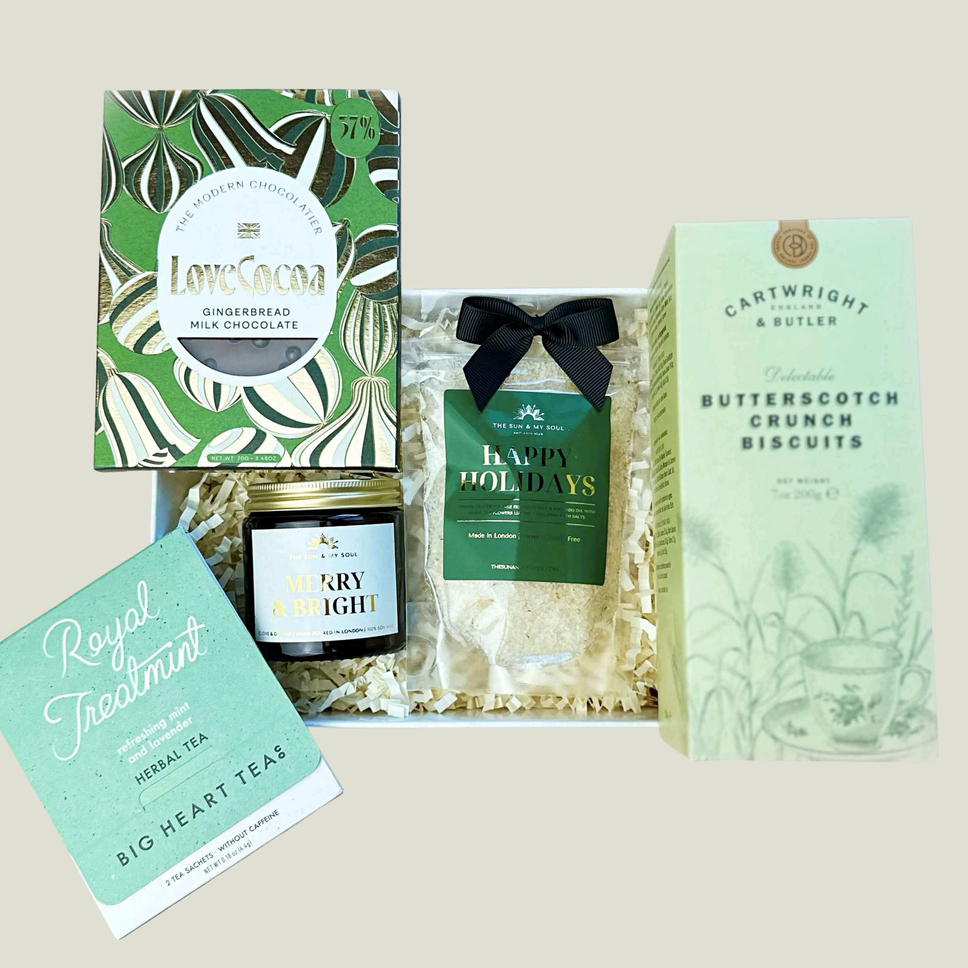 Collection of holiday-themed products including chocolate, tea, and cookies on a light background