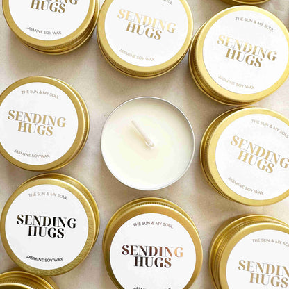 Candle tins with 'Sending Hugs' label on a light background