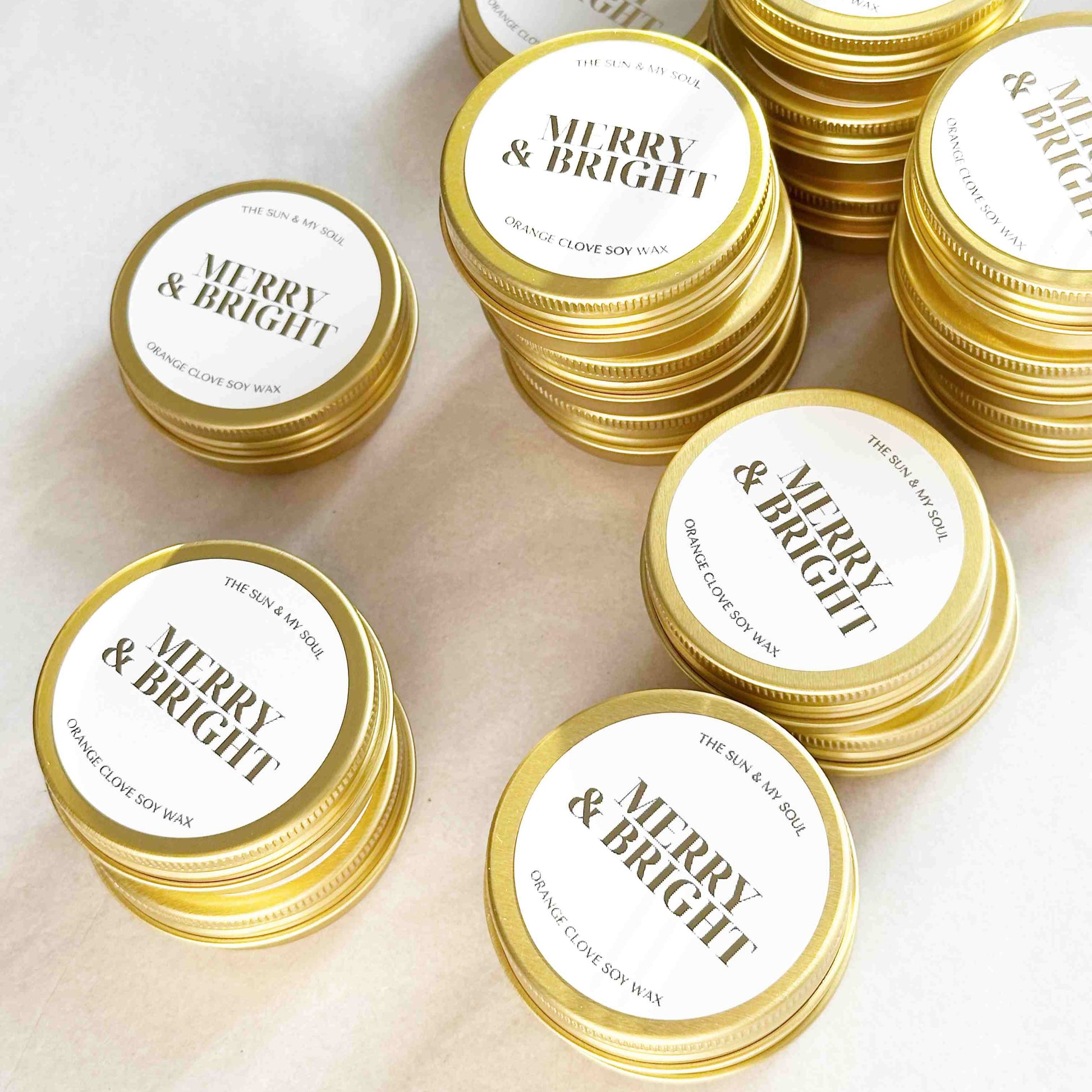 Gold tins with 'Merry & Bright' labels on a light background
