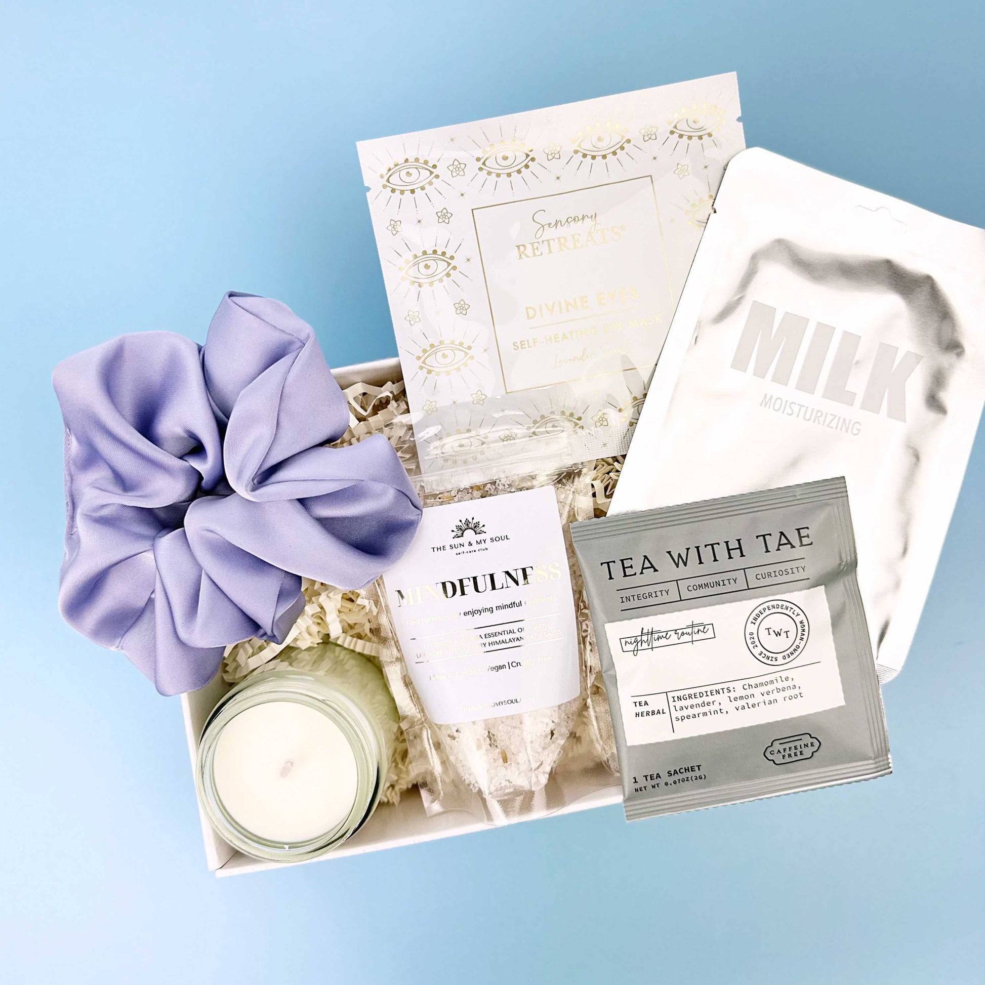 Gift set with tea, candle, and scrunchie on a blue background