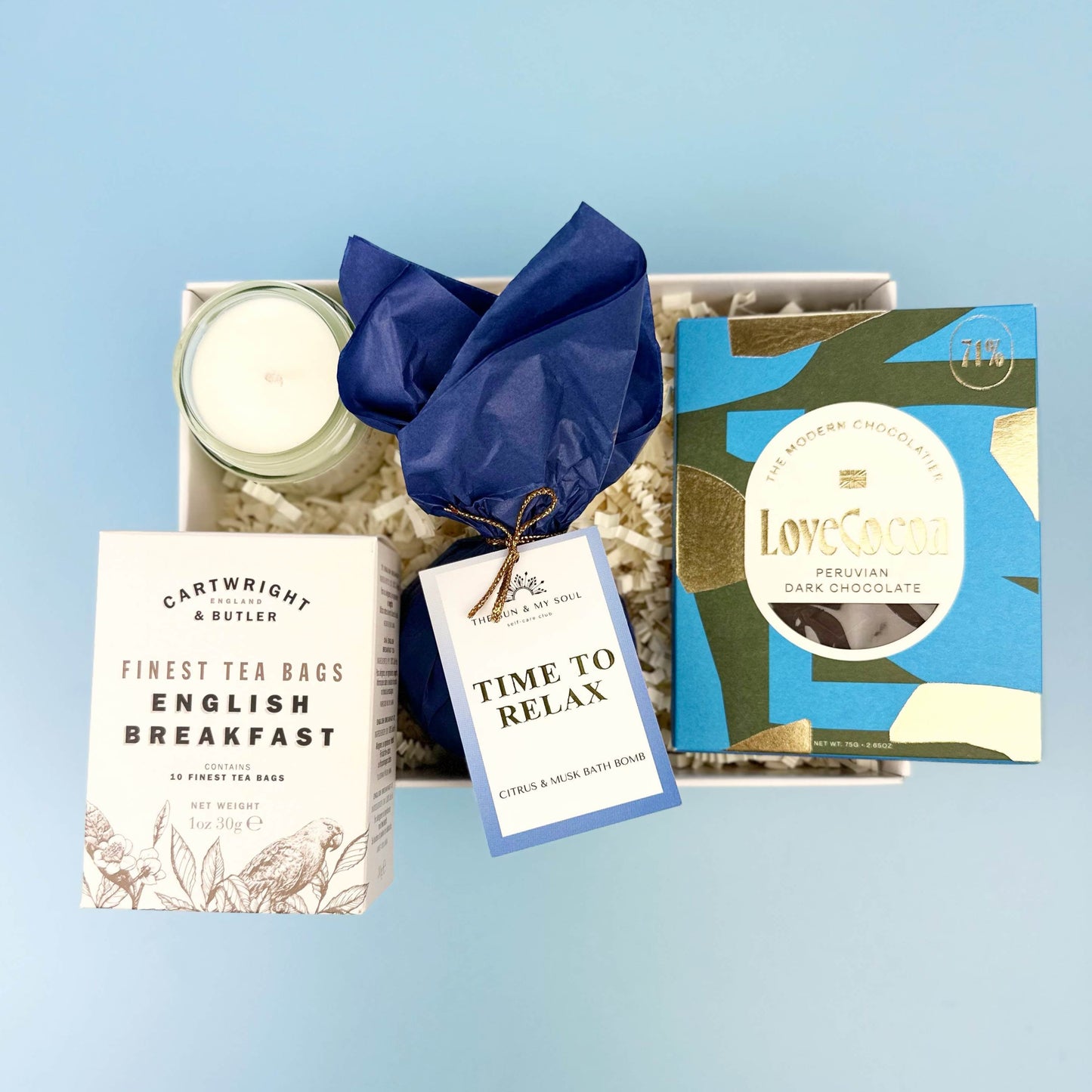 Gift set with tea, chocolate, and candle on a light blue background