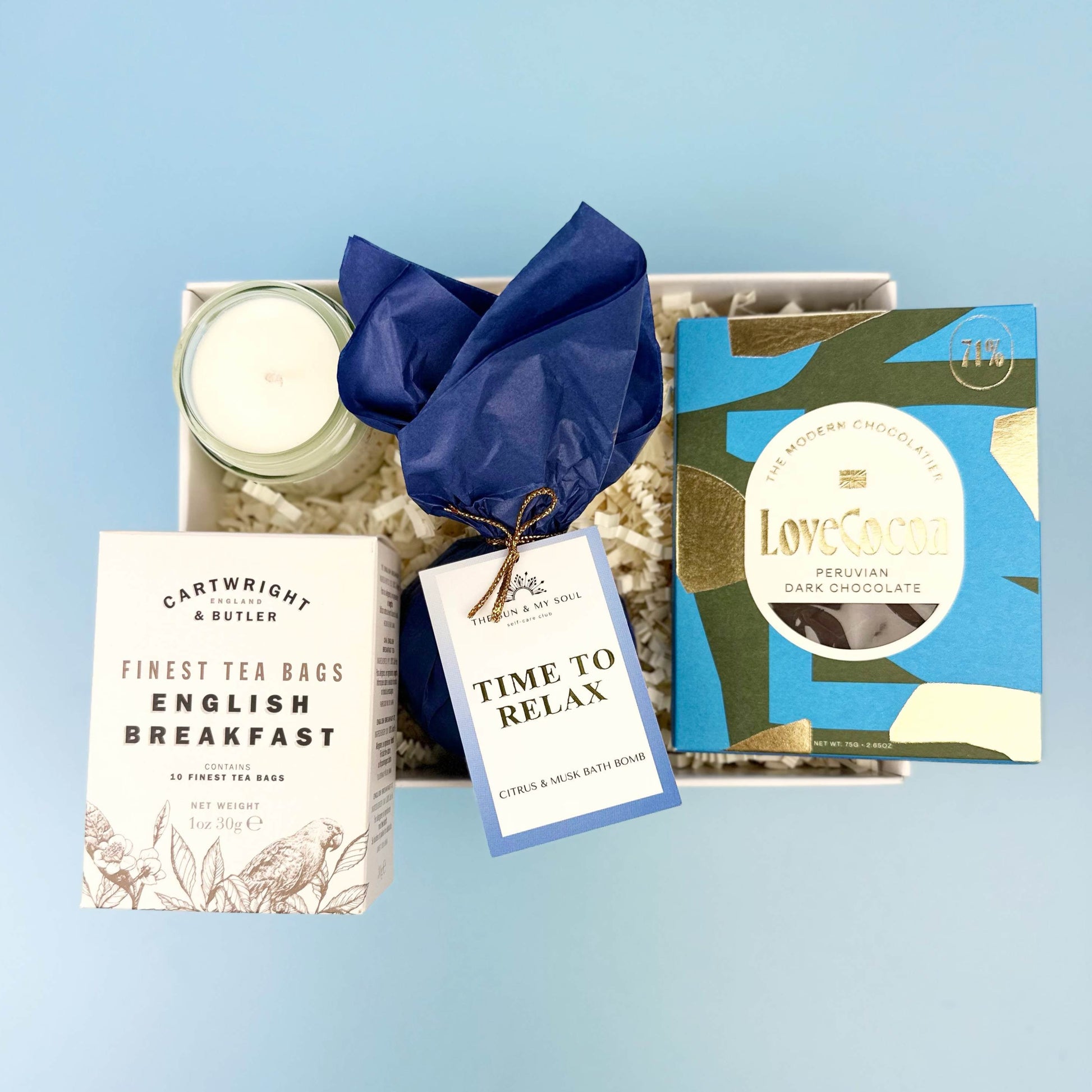 Gift set with tea, chocolate, and candle on a light blue background