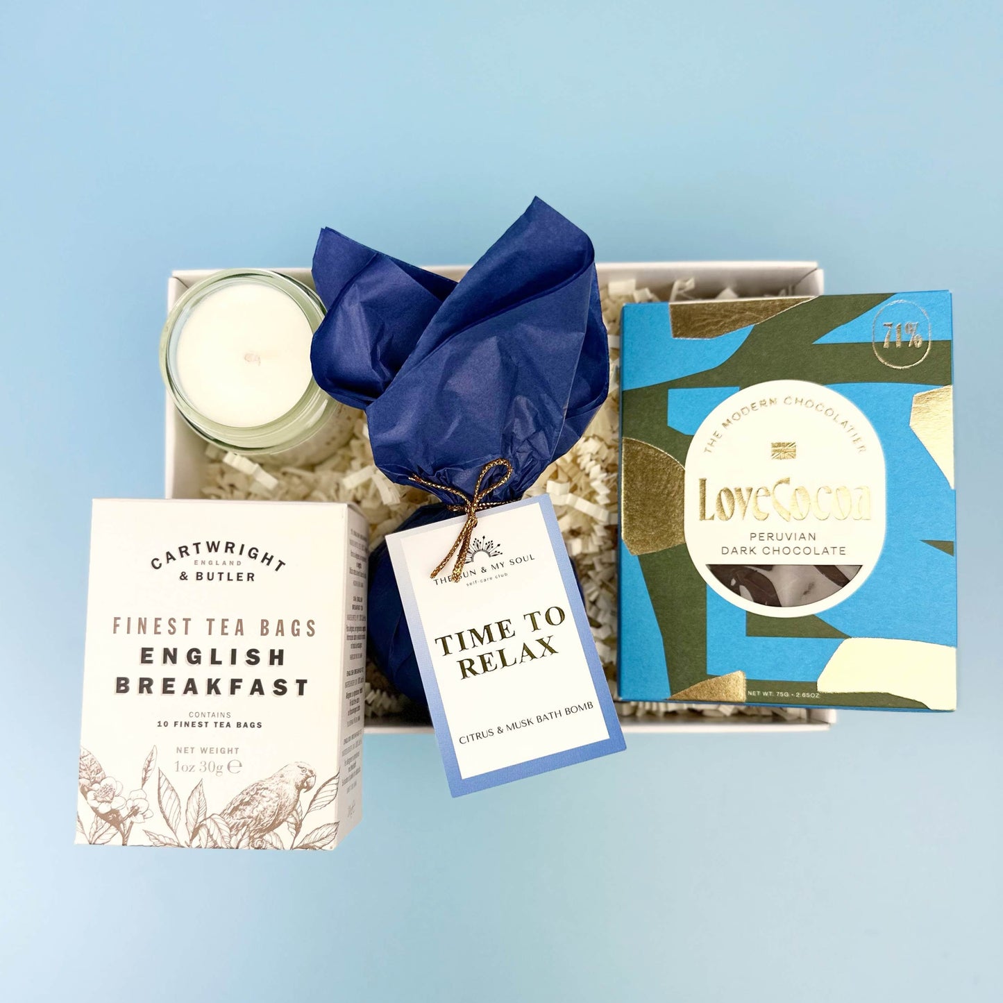 Gift set with tea, chocolate, and candle on a light blue background