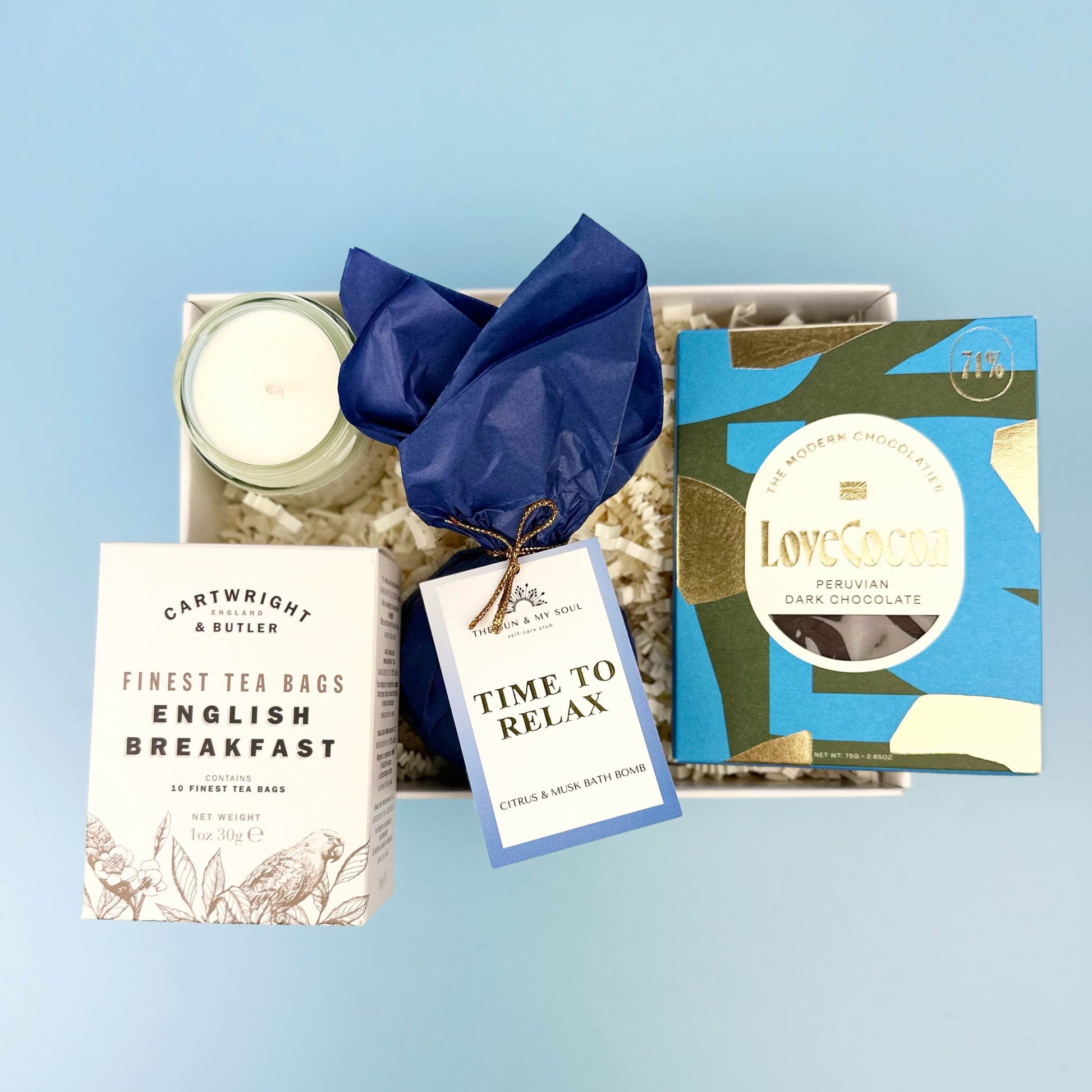 Gift set with tea, chocolate, and candle on a light blue background