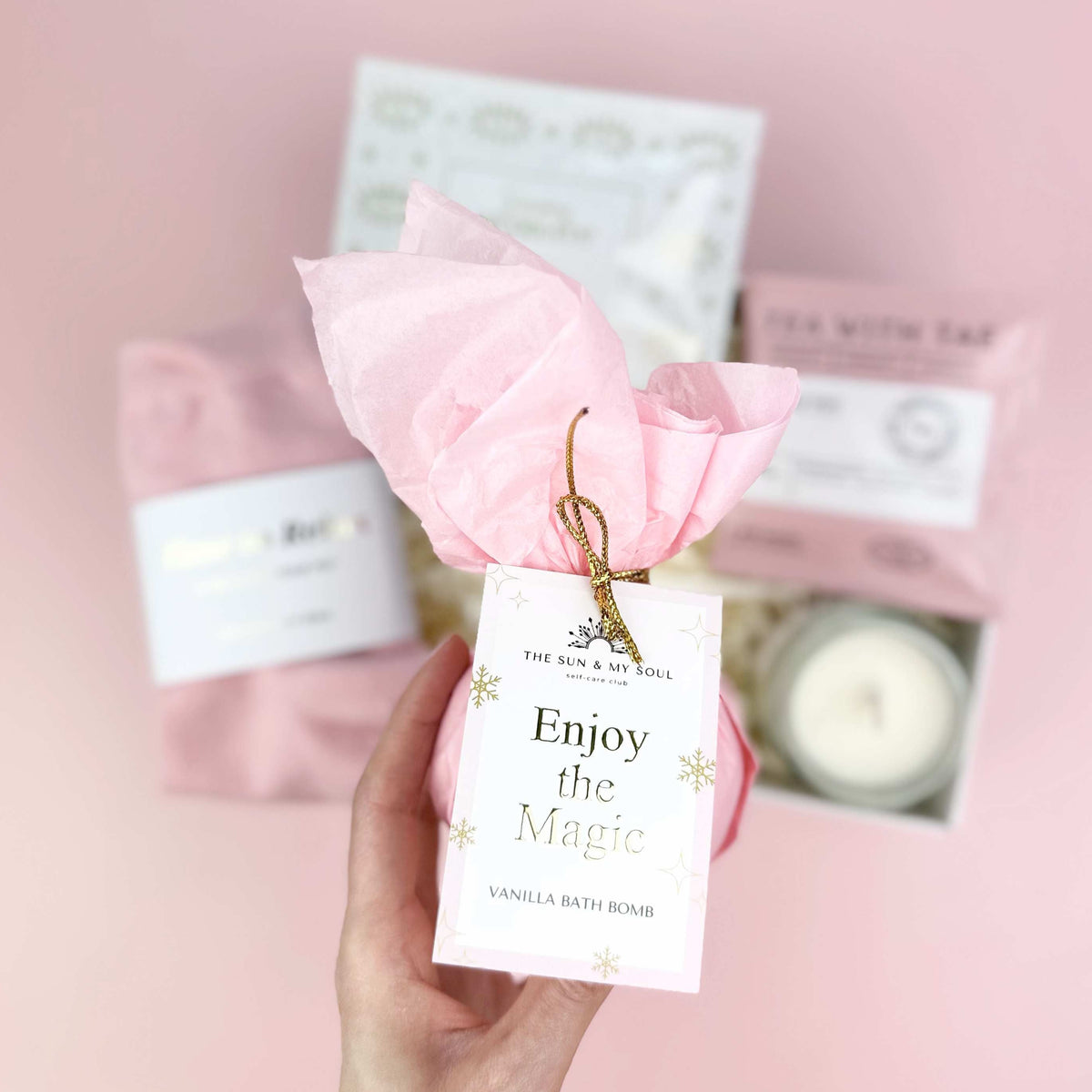 Pink rose with 'Enjoy the Magic' tag held against a pink background