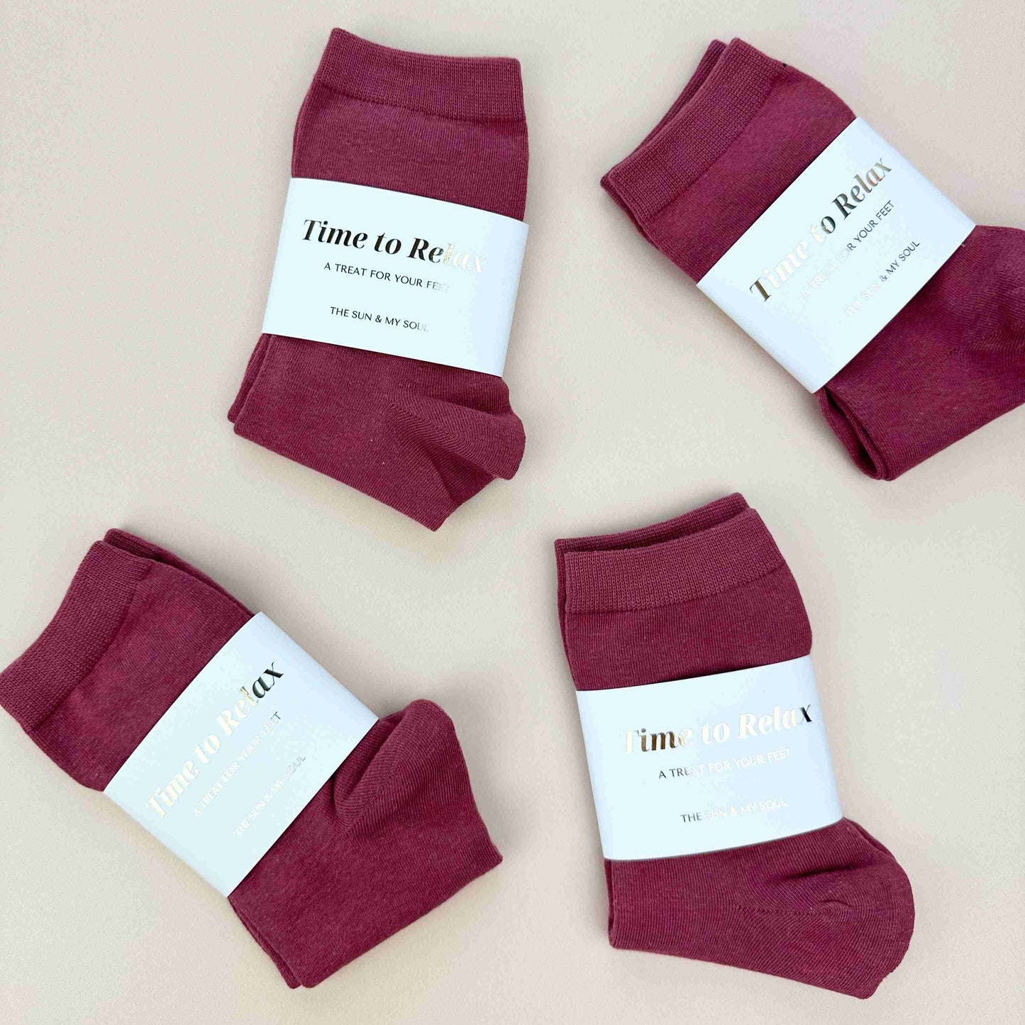 Four pairs of maroon socks with labels on a beige background
