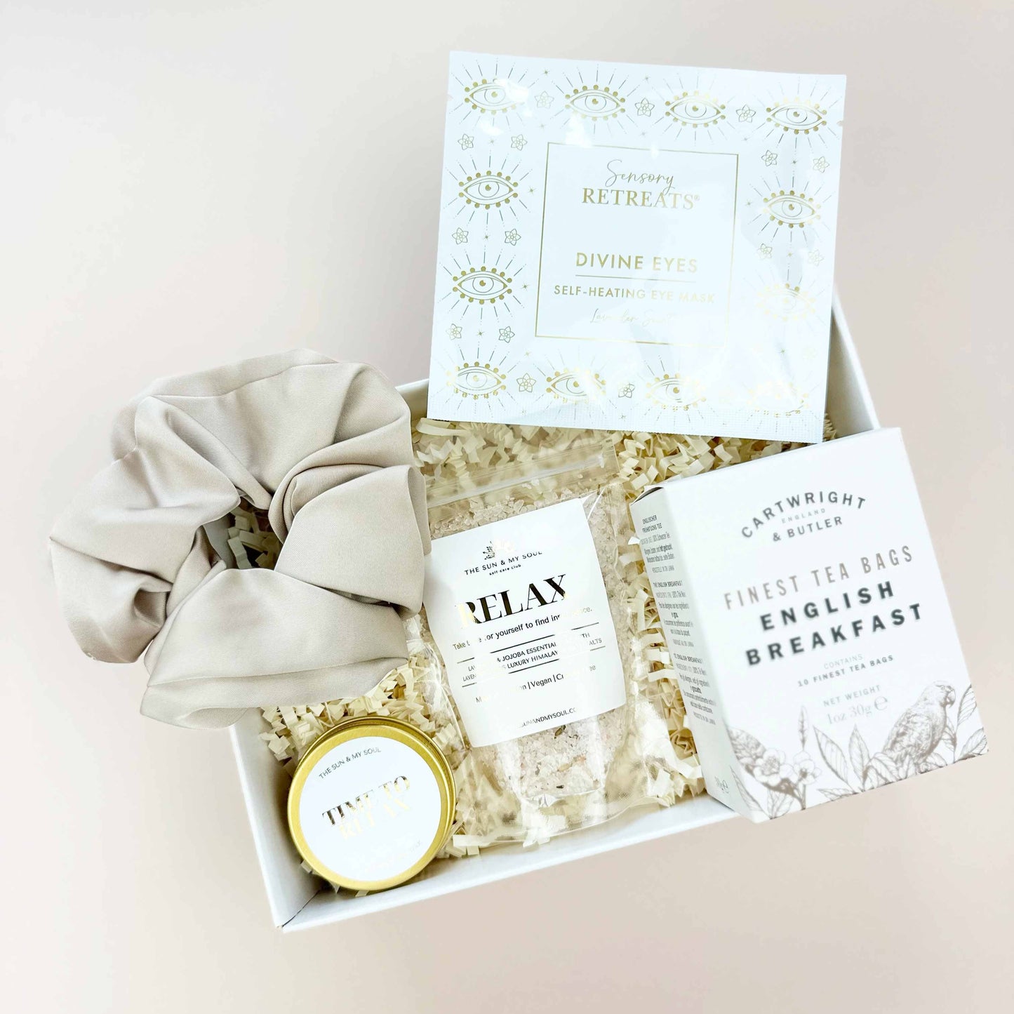 Gift set with a scrunchie, tea bags, and a small round item on a light background