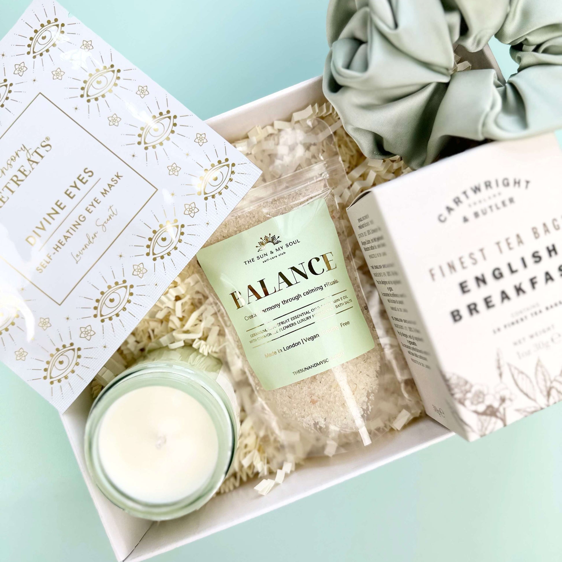 Gift set with a candle, soap, and scrunchie on a light blue background