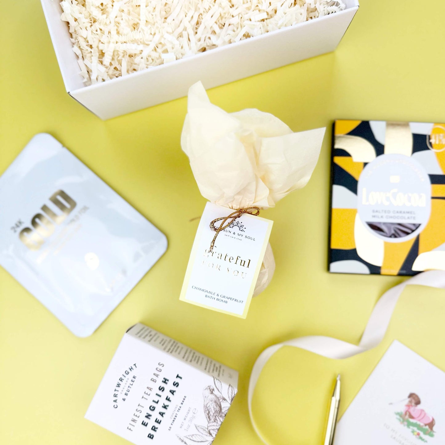 Box of popcorn, gift cards, and a small bouquet on a yellow surface