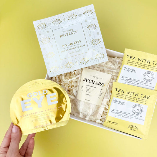 Collection of eye care products including a yellow eye mask, packets, and a box on a yellow background.