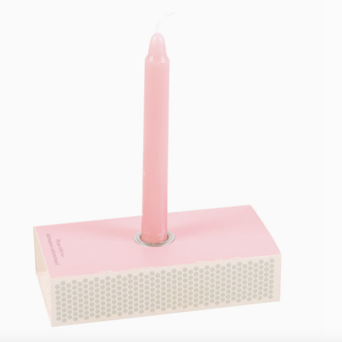 Pink candle on a pink holder with a white background