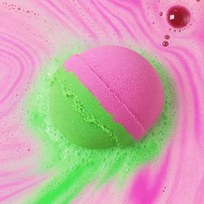 Pink and green bath bomb in a swirling pink and green liquid.