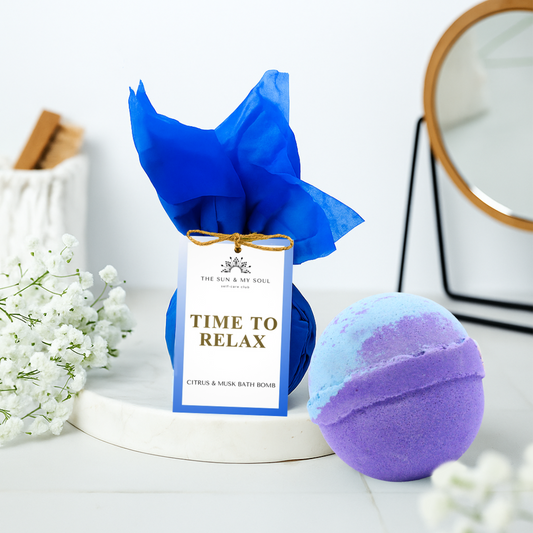 Blue and purple bath bomb with a decorative bow and 'Time to Relax' tag on a white surface.