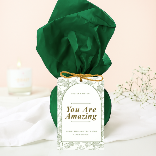 Green satin headband with 'You Are Amazing' tag on a light pink background