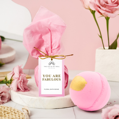 Bath bomb with 'You Are Fabulous' tag and pink roses on a light pink background