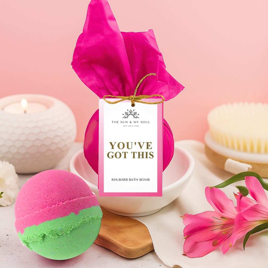 Pink and green bath bomb with 'You've Got This' packaging on a pink background