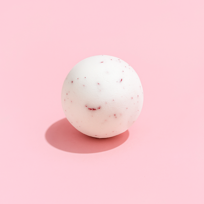 White bath bomb with red specks on a pink background