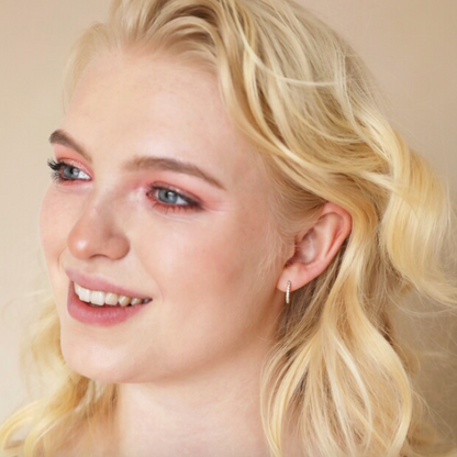 Close-up of a person with blonde hair and pink makeup on a beige background