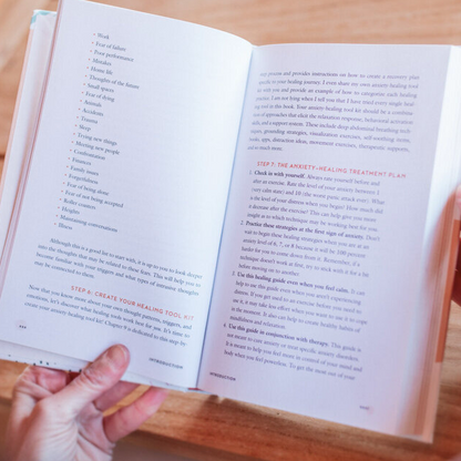 Open book with text held by hands on a wooden surface