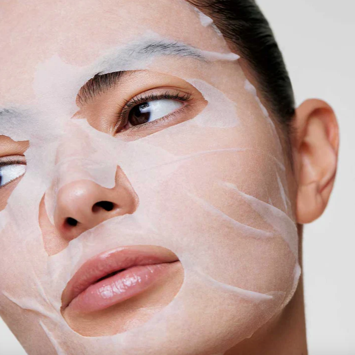 Person applying a face mask with a neutral background