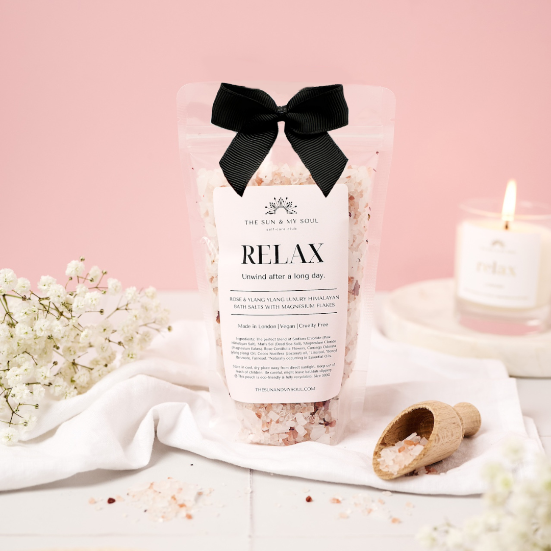 Bag of bath salts labeled 'Relax' with a black bow on a pink background