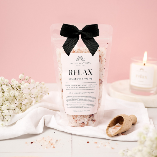 Bag of bath salts labeled 'Relax' with a black bow on a pink background