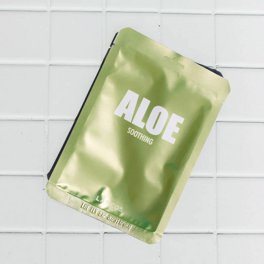 Green aloe vera sheet mask on a white tiled background