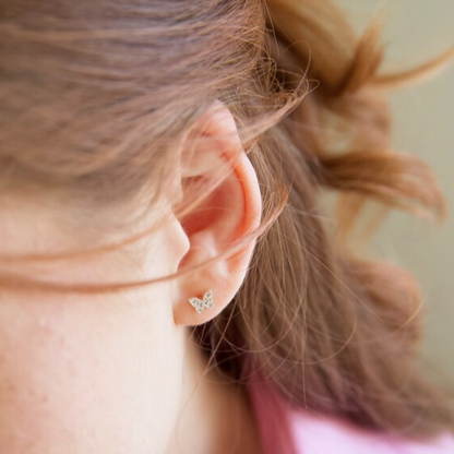 Close-up of a person wearing a diamond stud earring with blurred background