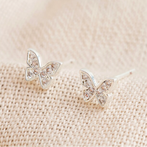 Butterfly-shaped earrings on a beige fabric background
