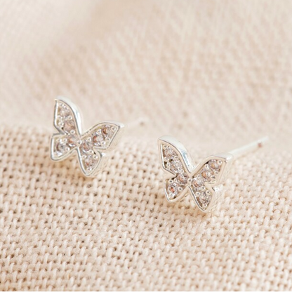 Butterfly-shaped earrings on a beige fabric background