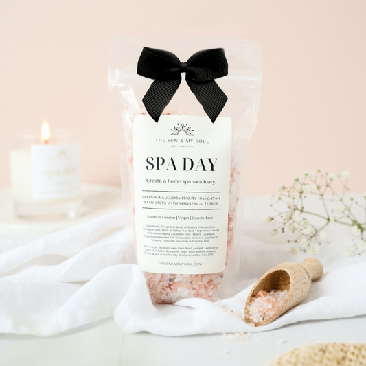 Spa day product with a black bow, candle, and bath accessories on a soft background